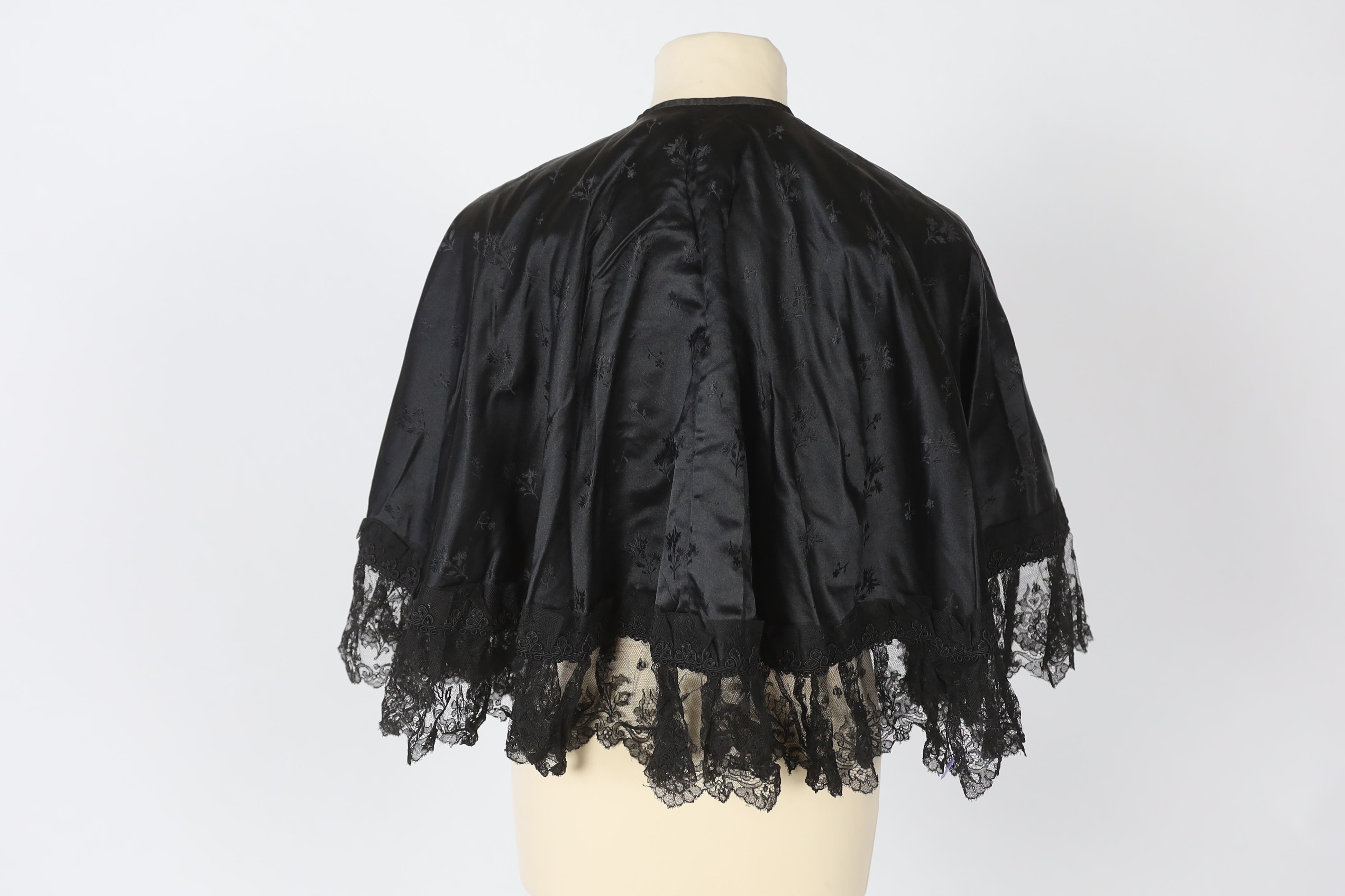 Two ladies Victorian black satin and lace, bead trimmed bodices, together with a black lace cape, a black satin cape, a small collection of coloured feathers and a child’s white worked pinafore